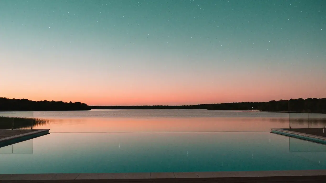 cinematic photograph of an infinity-edge pool beside a calm lake, under a starry night sky