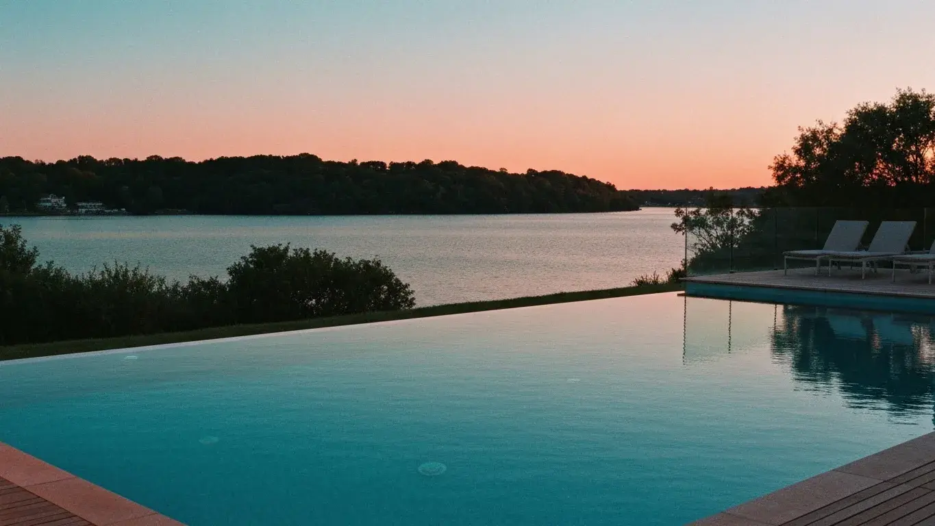 cinematic photograph of an infinity-edge pool beside a calm lake, at blue-hour dusk