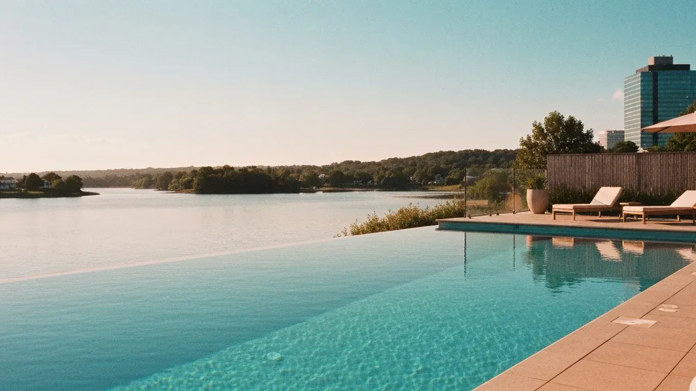 inviting lifestyle photograph of an infinity-edge pool beside a calm lake, at golden hour