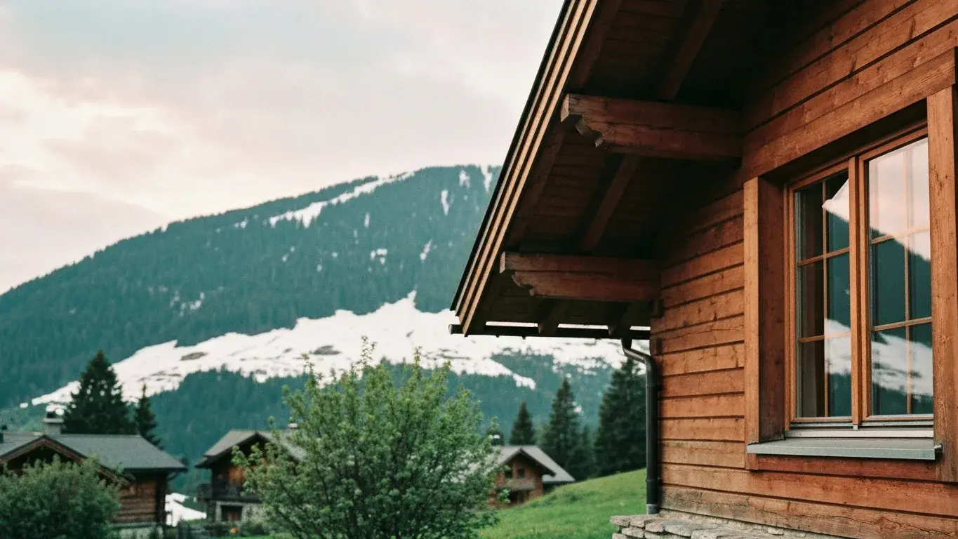 intimate exterior detail photograph of a lakefront timber house set in snowy alpine slopes, a soft overcast afternoon, lush summer