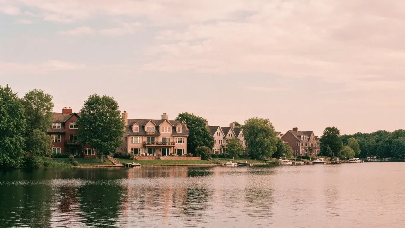 three-quarter architectural exterior photograph of a downtown loft conversion set in the edge of a glassy lake, a soft overcast afternoon, lush summer