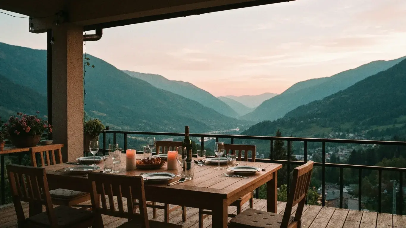 atmospheric wide photograph of an outdoor dining table set for dinner overlooking a mountain valley, on a warm morning